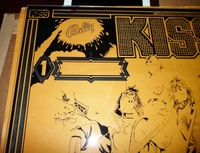 Image # 62113: KISS Partially Screened Backglass - Upper Left 
(First the mirroring was applied, then the black. This clear glass is resting upon brown paper.)