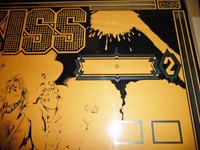 Image # 62114: KISS Partially Screened Backglass - Upper Right 
(First the mirroring was applied, then the black. This clear glass is resting upon brown paper.)
