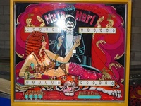 Image # 27825: Mata Hari Backglass with Dagger Inscription 
(This game has several serial numbers:1110 is stamped externally on both the cabinet side and head.1112 is tagged on the inside cabinet motor board.1113 is tagged inside the backbox.1116 is tagged under the playfield.)