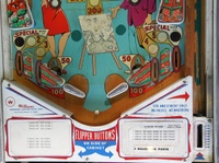 Image # 63442: Moulin Rouge Early Production Lower Playfield 
(The upside-down map depicted on the artist's easel is an after-factory adhesive. The mini-post between the flippers does not appear on the manufacturer's flyer and may be an after-factory addition. Serial number 19267.)