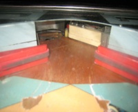 Image # 40608: Post Time Outhole Gate for Extended Play 
(When optioned for extended play, a flipper-like gate under the apron routes the draining ball away from the outhole to a kicker which propels the ball upwards through the flippers and back into play.)