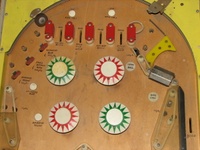 Image # 41030: See Saw Whitewood Upper Playfield 
(Near the exposed light bulbs are penciled circles suggesting where the bulbs ought to be. The loose ball guide rubber would be fitted around a post missing from the nearby screw hole.)