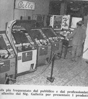 Image # 36803: Slap Stick Magazine Photo 
(From the Italian coin-op magazine Automat of a coin-op show held in Milan, Italy on April 14-25, 1975. In the background is a cabinet view of Bally's 1974 'Bali' bingo machine.)