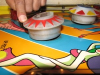 Image # 59678: Carnival Pop Bumper Activation 
(The pop bumper is manually operated to simulate a ball hitting it from the direction of the upper playfield. A nearby pop bumper is in normal position. Serial number 0400.)