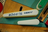 Image # 50840: Cowboy Jumbo Flipper Comparison 
(Gottlieb referred to their 3-inch flipper as a 'jumbo flipper' and it is shown here for size comparison. The Chicago Coin jumbo flippers on this playfield are reversed, causing the printing to be upside down.)