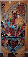 Image # 56625: Demolition Man Stripped Playfield - Labeled Inserts 
(The three round orange inserts and the larger white rectangular insert on the left side of the playfield are labeled with point values or text.)